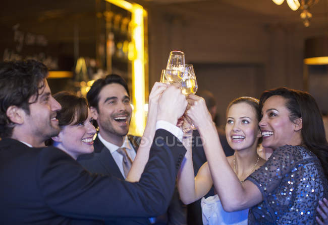 Des amis bien habillés grillant des flûtes à champagne — Photo de stock