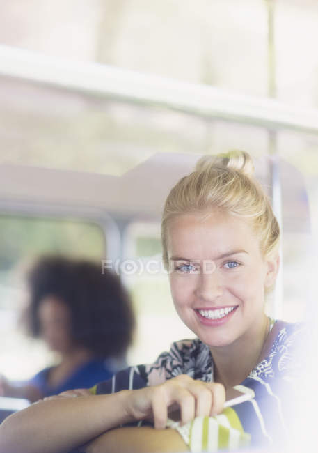 Портрет улыбающейся блондинки, держащей мобильный телефон в автобусе — стоковое фото