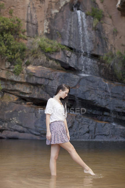 Woman wading in pool against rock — Stock Photo
