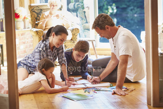 Dibujo familiar y colorear en el suelo en la sala de estar - foto de stock