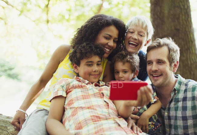 Familia multi-generación tomando selfie con cámara de teléfono en el bosque - foto de stock