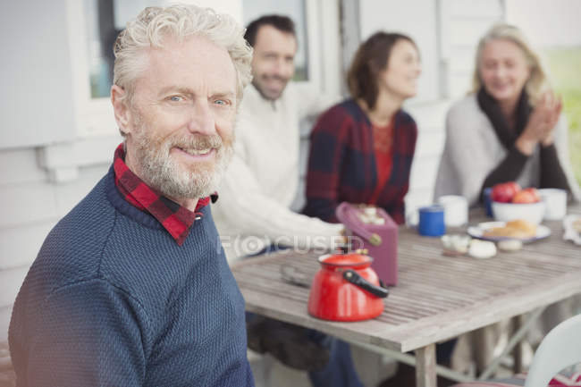 Retrato sonriente hombre mayor disfrutando del desayuno con la familia en el patio - foto de stock