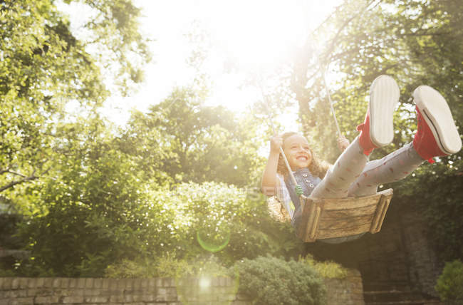 Беззаботная девушка, качающаяся на солнечном заднем дворе — стоковое фото