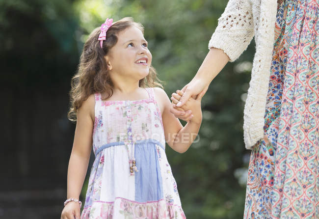 Menina sorridente no vestido segurando a mão da mãe — Fotografia de Stock