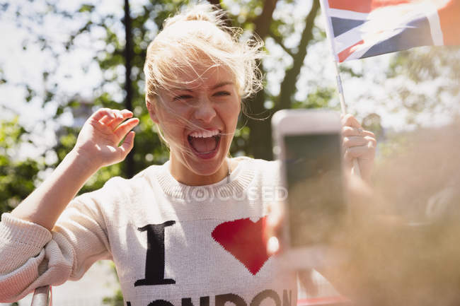 Entusiasta donna sventola bandiera britannica essere fotografato — Foto stock