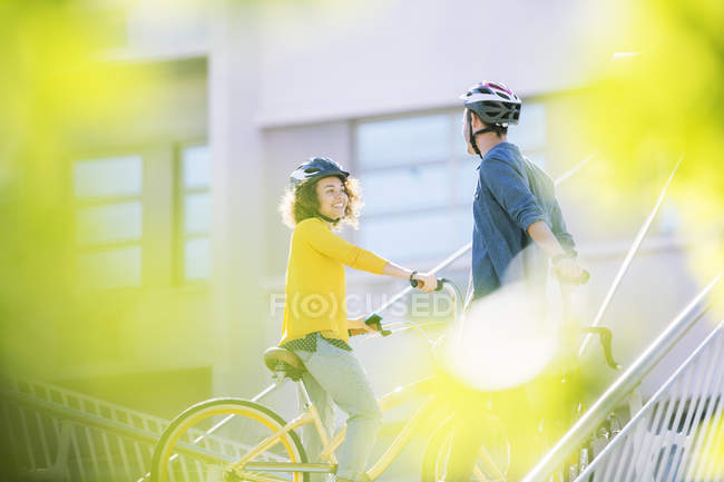 Homme et femme avec des casques sur les vélos parler — Photo de stock