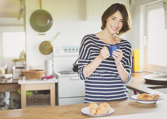 Портрет усміхненої жінки, що п'є каву на кухні — стокове фото