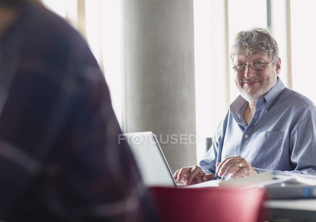 Hombre sonriente retrato trabajando en el portátil en el aula de educación de adultos - foto de stock