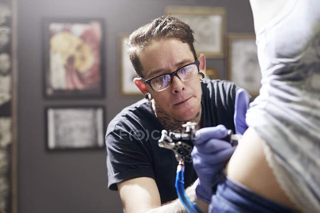 Tatuagem artista tatuando mulher de volta ao estúdio — Fotografia de Stock