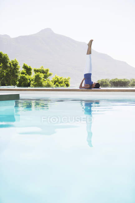 Jeune femme attrayante pratiquant le yoga au bord de la piscine — Photo de stock
