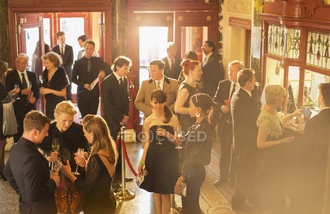 Gente bien vestida bebiendo champán en el vestíbulo del teatro - foto de stock