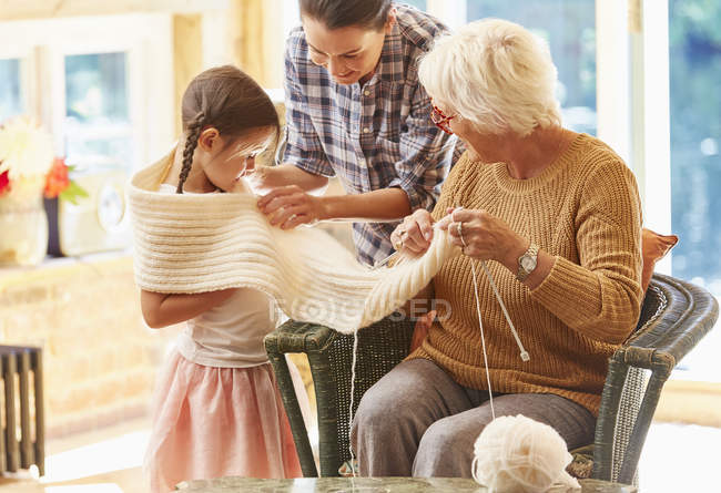 Grandmother knitting scarf around granddaughter — Stock Photo