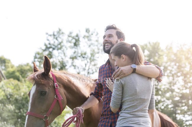Pareja sonriente abrazándose cerca del caballo - foto de stock