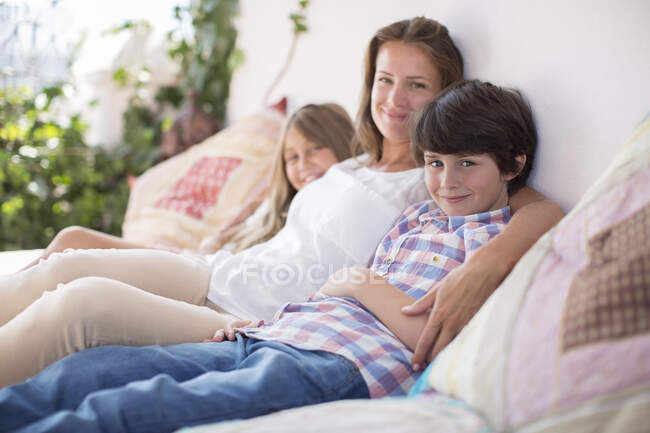 Мать и дети отдыхают на диване во внутреннем дворике — стоковое фото