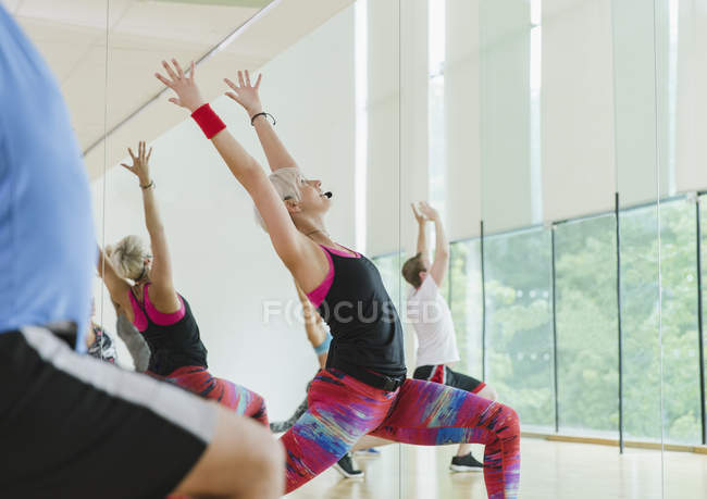 Fitness instructor leading aerobics class in high lunge — Stock Photo