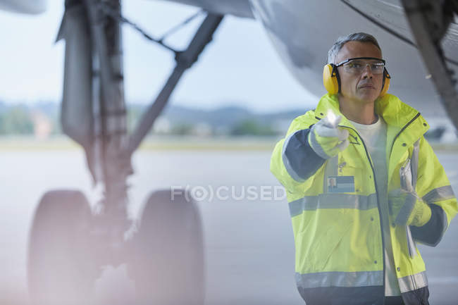 Air traffic controller with flashlight under airplane on airport tarmac — Stock Photo