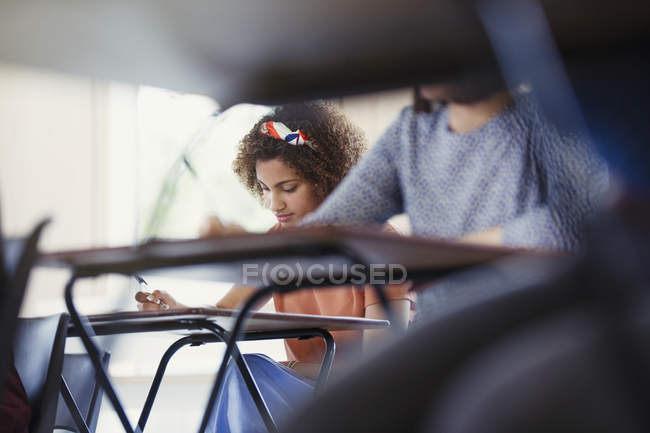 Female college student taking test at desk in classroom — Stock Photo