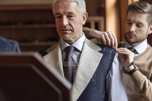 Портной примерки бизнесмен для костюма в магазине мужской одежды — стоковое фото