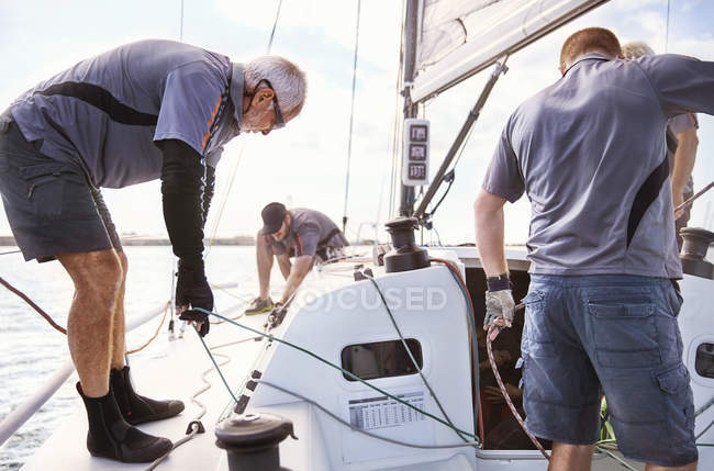 Homens navegando ajustando veleiro aparelhamento — Fotografia de Stock