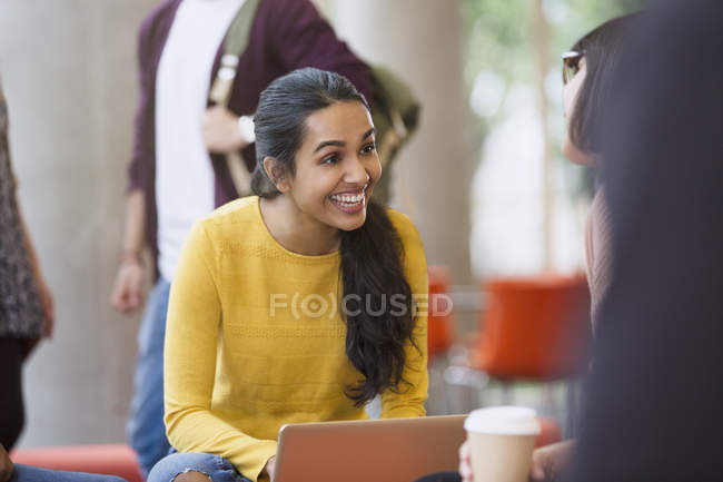 Улыбающиеся студентки колледжа с кофе и ноутбуком — стоковое фото