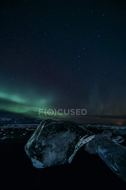 Luci settentrionali sul paesaggio notturno ghiacciato e sul ghiacciaio di Jokulsarlon, Islanda — Foto stock