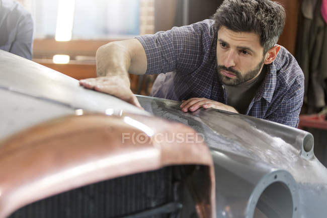 Focused mechanic examining classic car panel in auto repair shop — Stock Photo