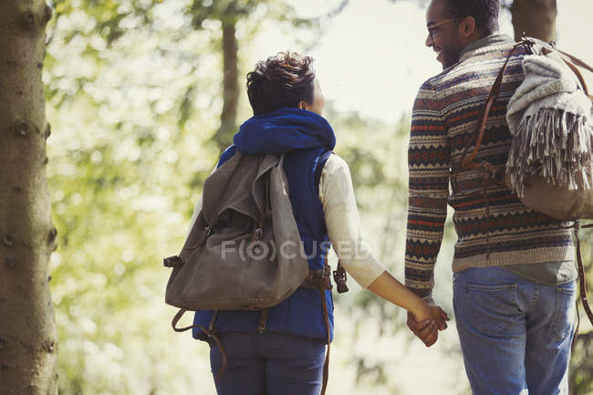 Couple with backpacks holding hands hiking in woods — Stock Photo