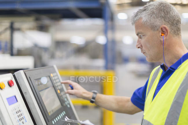 Worker operating machinery at control panel in steel factory — Stock Photo