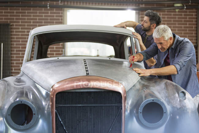Mechanics rebuilding classic car in auto body shop — Stock Photo