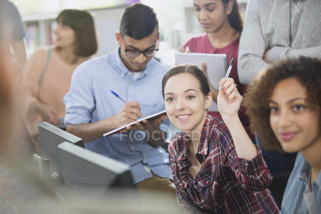 Studente universitario alzando la mano in aula laboratorio informatico — Foto stock