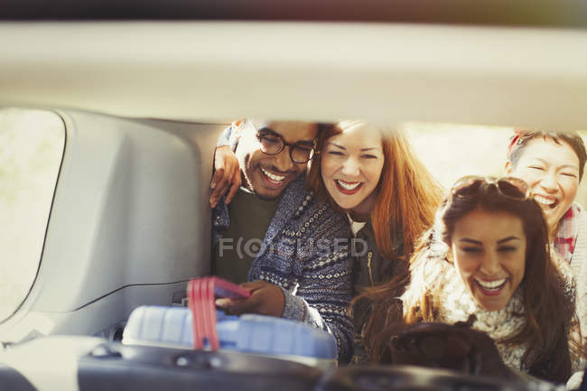 Друзья разгружают кулер с заднего сиденья машины — стоковое фото