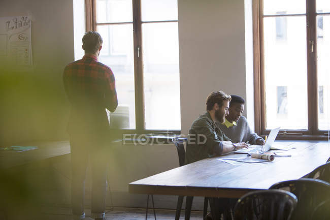 Creative business people working at laptop in office — Stock Photo