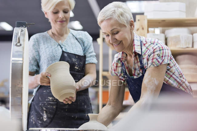 Mulher sênior segurando cerâmica no forno em estúdio — Fotografia de Stock