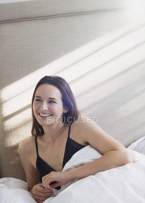 Lächelnde Frau liegt im Bett und schaut weg — Stockfoto