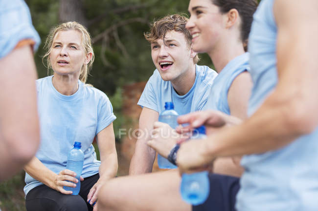 Tired team resting and drinking water at boot camp — Stock Photo