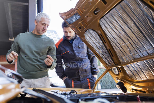 Mechanics checking oil dipstick in auto repair shop — Stock Photo