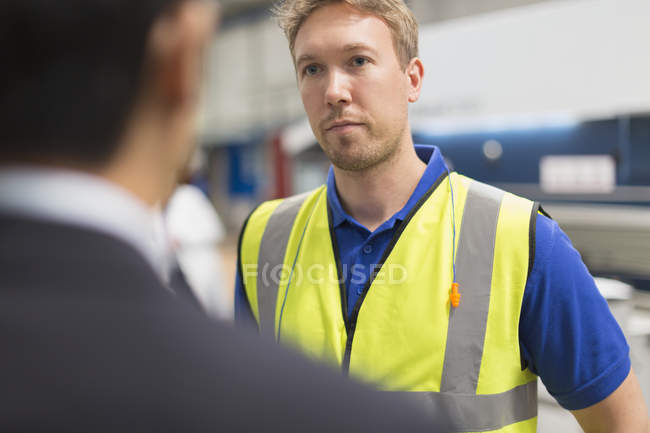 Серйозний працівник, який слухає менеджера на металургійному заводі — стокове фото