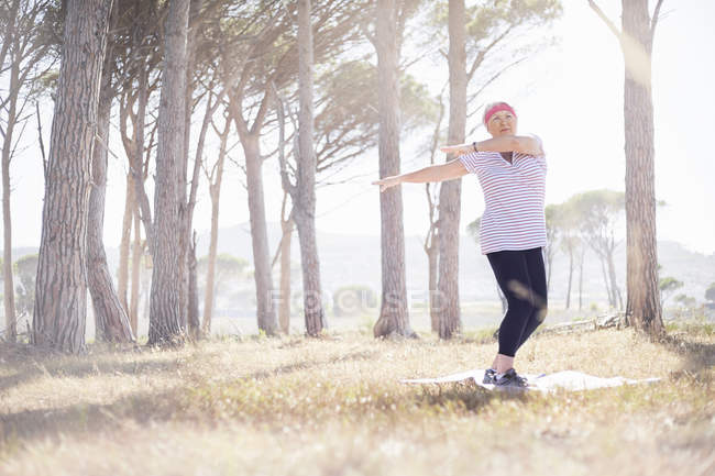 Mulher sênior praticando ioga no parque ensolarado — Fotografia de Stock
