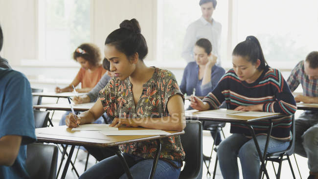 College students taking test at desks in classroom — Stock Photo
