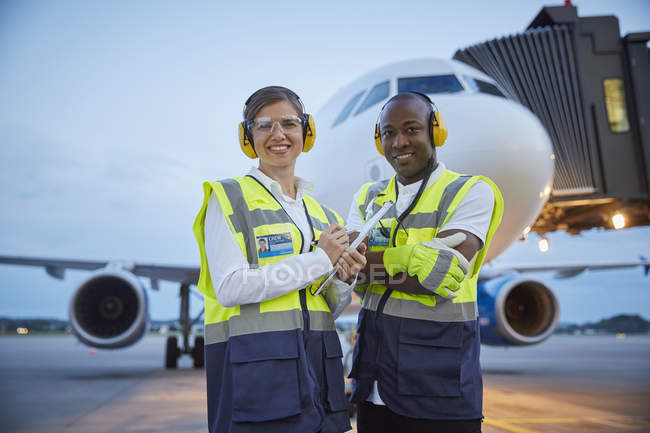 Retrato confiante pessoal da tripulação de terra do controle de tráfego aéreo perto do avião no asfalto do aeroporto — Fotografia de Stock