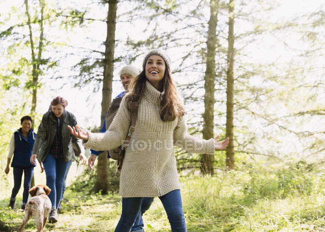 Sorrindo mulher caminhando com amigos na floresta — Fotografia de Stock