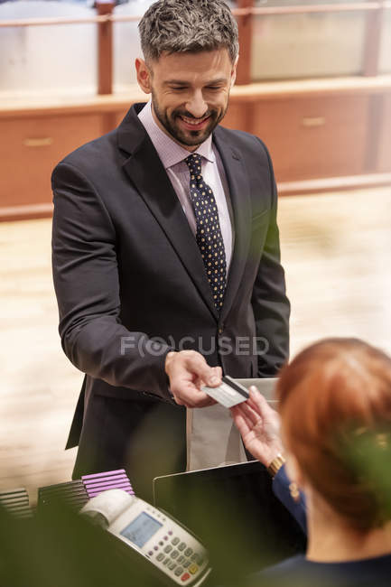Businessman paying clerk with credit cart at menswear shop — Stock Photo
