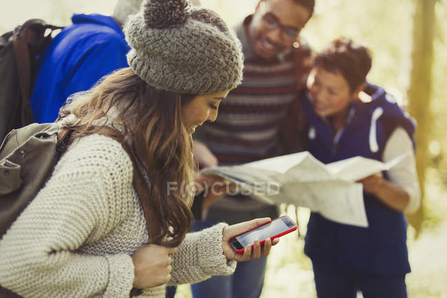 Friends hiking checking map and GPS on smart phone — Stock Photo