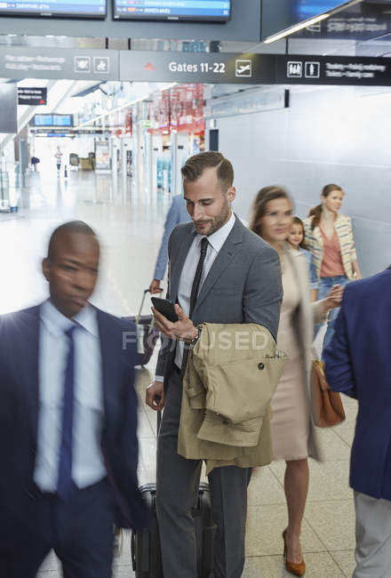 Empresario usando teléfono celular en el vestíbulo del aeropuerto - foto de stock