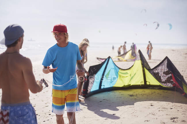 Homens preparando kiteboarding pipa na praia ensolarada — Fotografia de Stock