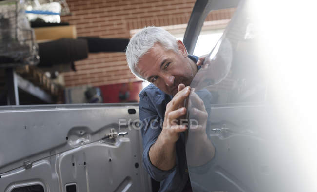 Mecánico examinando el panel del coche en taller de reparación de automóviles - foto de stock
