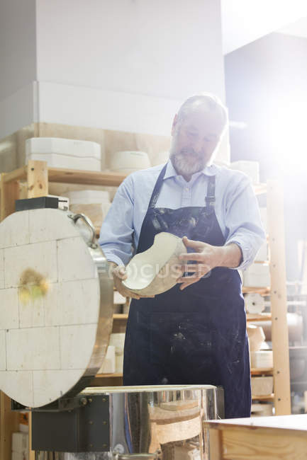 Man examining pottery at kiln in studio — Stock Photo