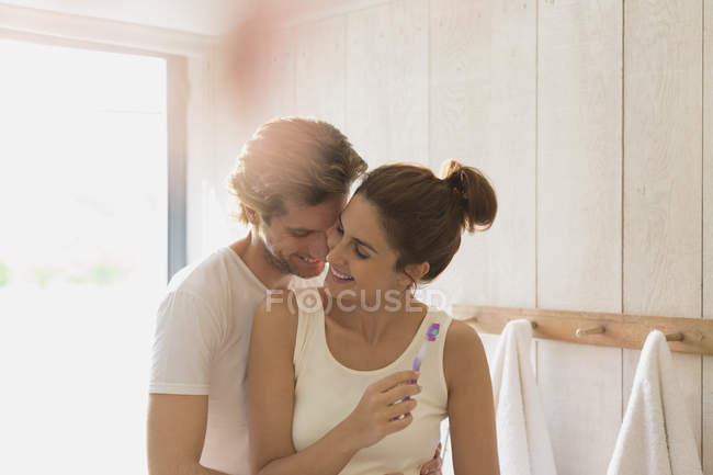 Casal afetuoso escovando dentes no banheiro ensolarado — Fotografia de Stock