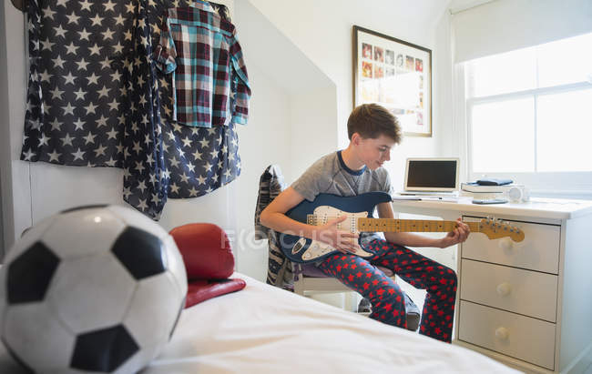 Boy playing electric guitar in bedroom — Stock Photo