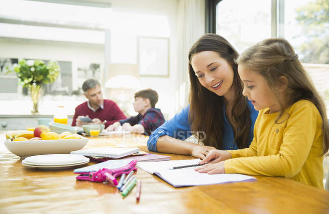 Mother and daughter doing homework at dining table — Stock Photo